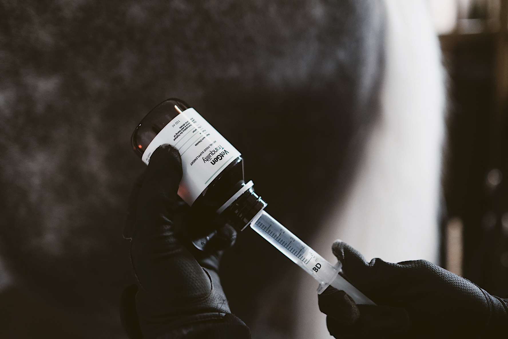 Gloved hands drawing VetGen Tranquility from its bottle into a dosing syringe